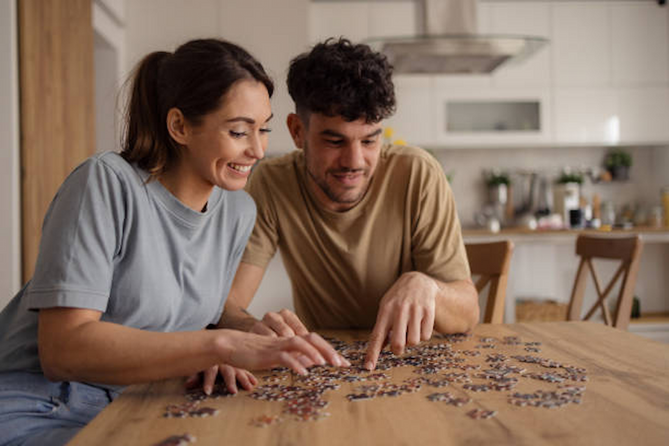 Una pareja haciendo un puzzle juntos en una mesa acogedora, iluminada por luz cálida.